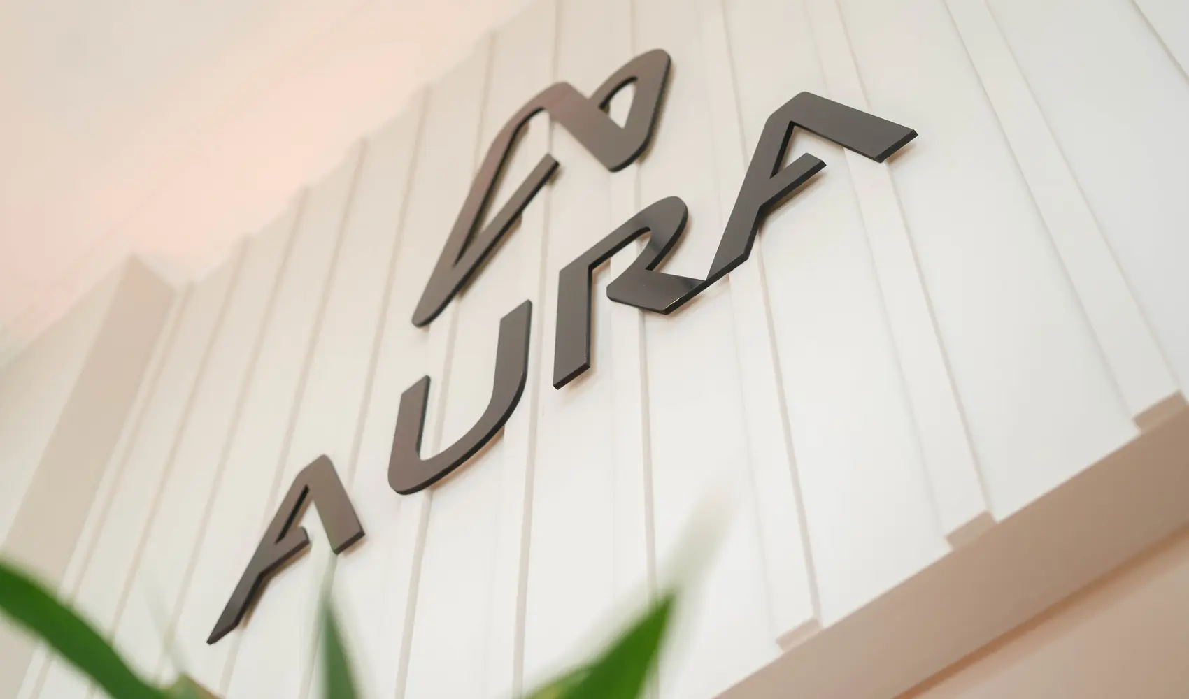 Logotipo da Aura Showroom aplicado em relevo na parede do showroom